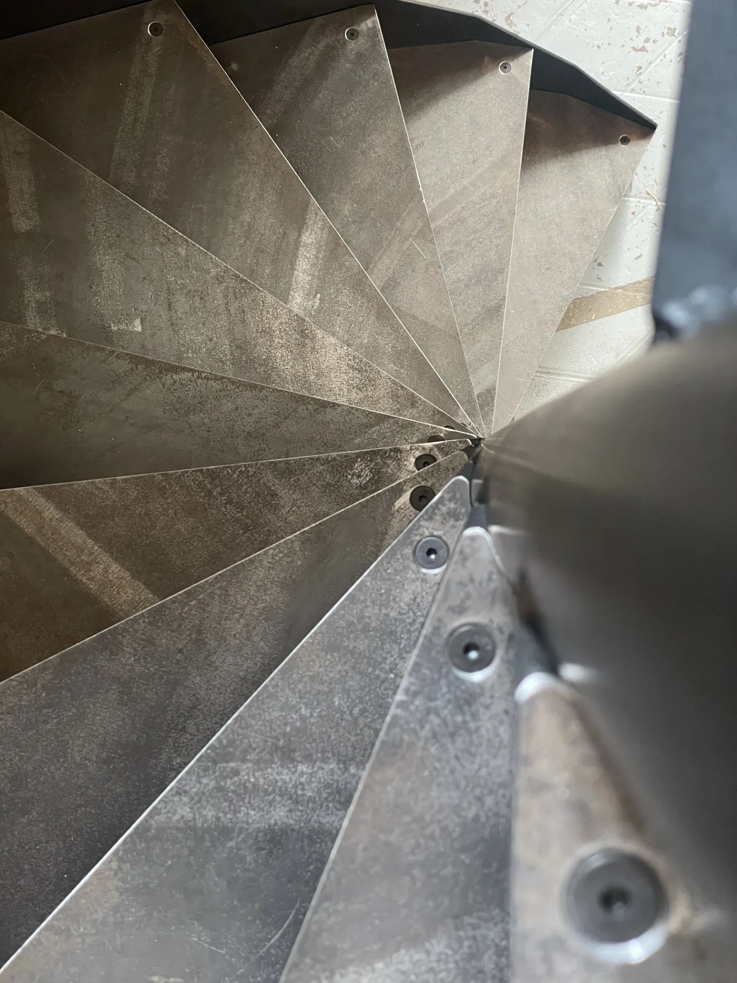Illustration d'un escalier en colimaçon à marches acier brut, épaisseur 12mm assemblées par boulonnage sur un fut Ø101,6 mm. Réalisation: Atelier Gracz